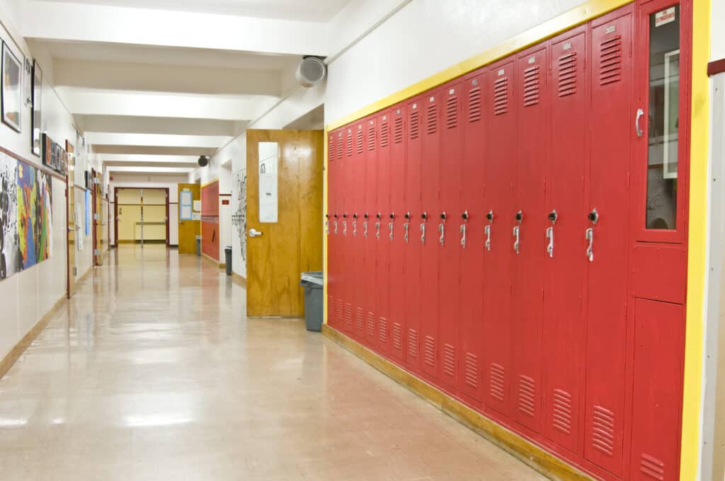 An empty highschool hallway with red lockers on the right side