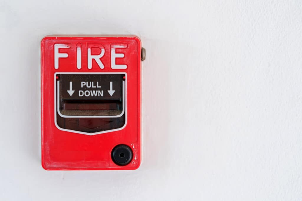 Switch to Fire alarm system on white wall background.