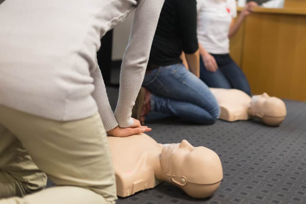 A group of students practicing CPR chest compressions on a dummy.